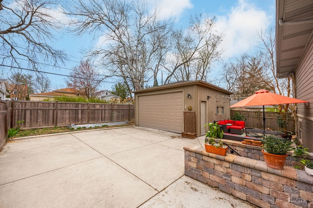 view of patio / terrace featuring an outdoor structure, a garage, and a fenced backyard