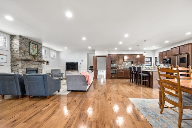 living area featuring a fireplace, recessed lighting, a wainscoted wall, and light wood-type flooring