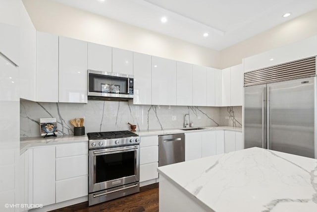 kitchen with white cabinets, appliances with stainless steel finishes, decorative backsplash, and a sink