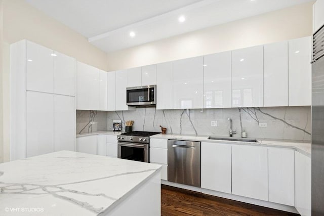 kitchen with modern cabinets, decorative backsplash, appliances with stainless steel finishes, and a sink