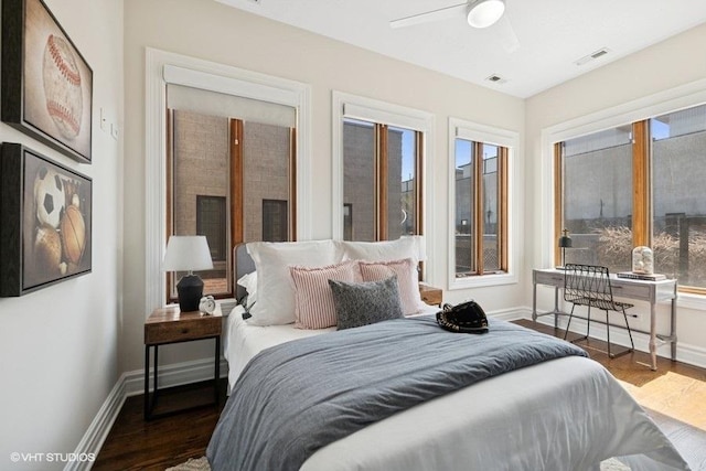 bedroom with wood finished floors, visible vents, baseboards, and multiple windows