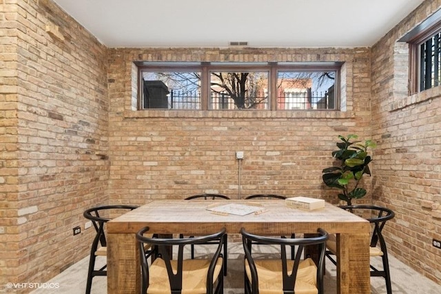dining room featuring brick wall and visible vents