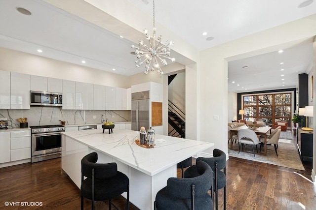 kitchen featuring stainless steel appliances, backsplash, light stone countertops, a breakfast bar, and a kitchen island