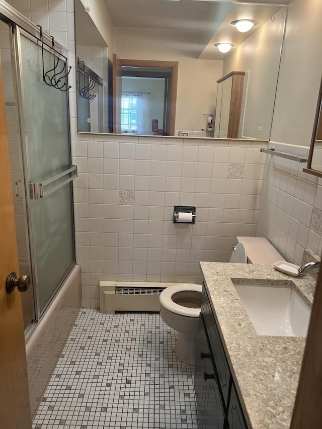 bathroom featuring a baseboard heating unit, tile walls, toilet, tile patterned floors, and shower / bath combination with glass door