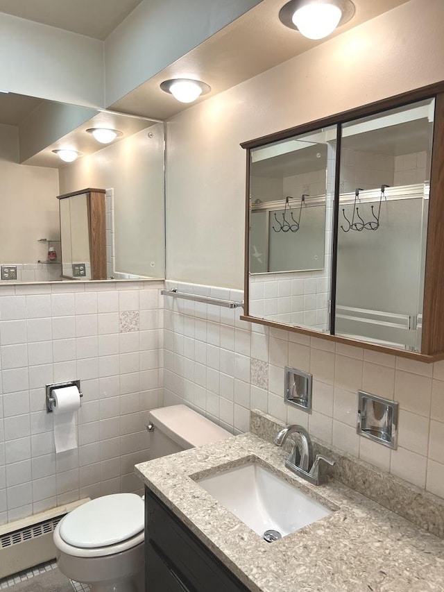 full bath with a baseboard radiator, toilet, tile walls, a shower with door, and vanity
