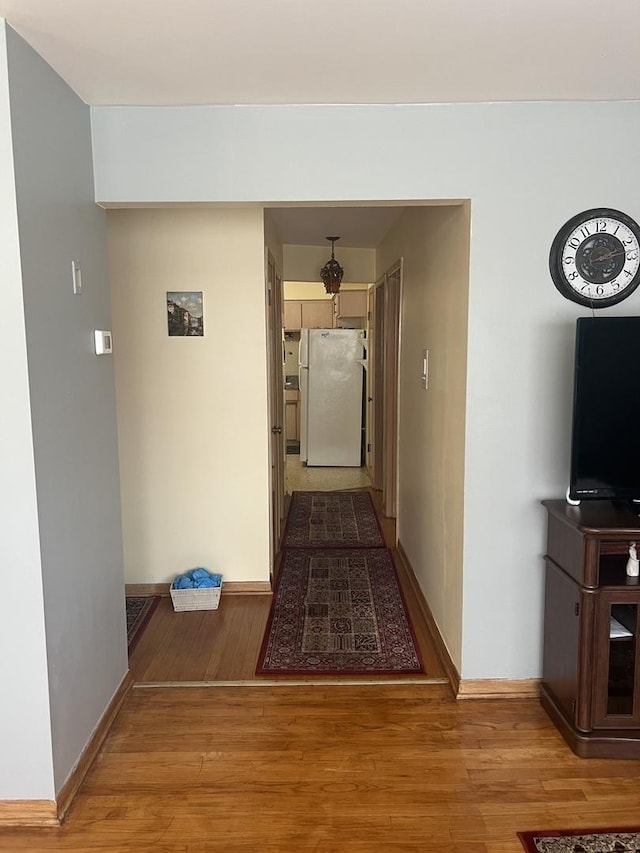 hallway featuring wood finished floors and baseboards