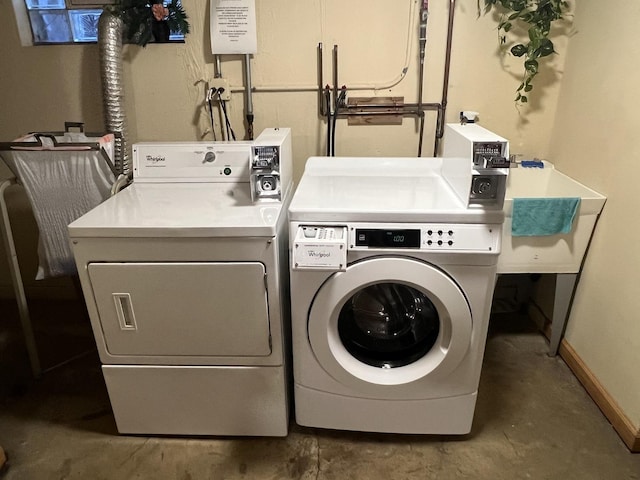 washroom with washer and clothes dryer, a sink, and baseboards