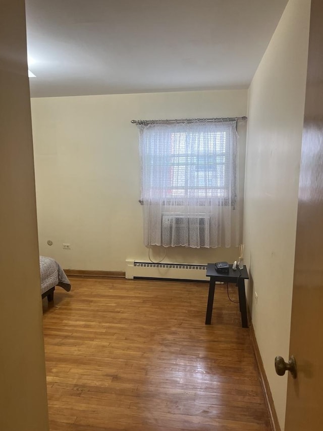 bedroom featuring a baseboard radiator, wood finished floors, and baseboards