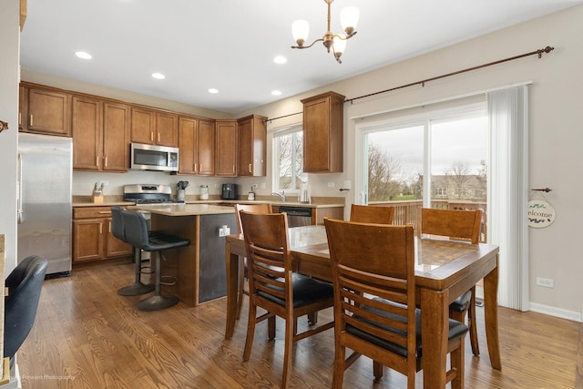 kitchen with a chandelier, brown cabinetry, light countertops, dark wood-type flooring, and appliances with stainless steel finishes