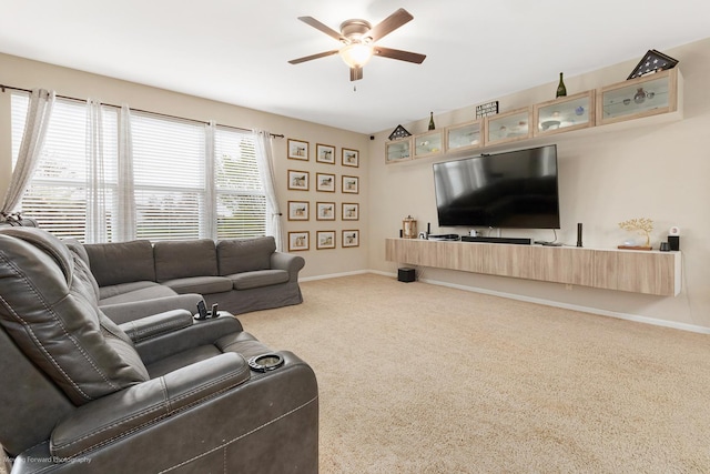 living area featuring baseboards, a ceiling fan, and carpet