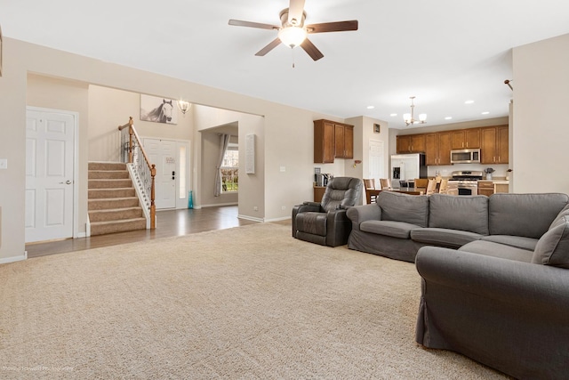 living area with recessed lighting, stairway, baseboards, light colored carpet, and ceiling fan with notable chandelier