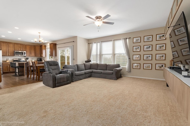 carpeted living room with baseboards, recessed lighting, and ceiling fan with notable chandelier