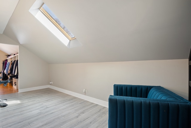 unfurnished room featuring light wood-type flooring, baseboards, and vaulted ceiling with skylight