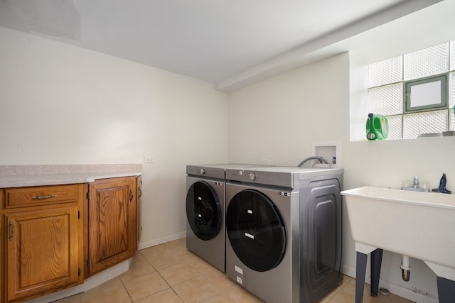 washroom with light tile patterned floors, cabinet space, a sink, and independent washer and dryer