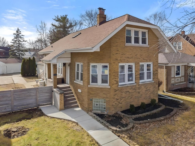 view of front of property with brick siding, a chimney, fence, and a gate