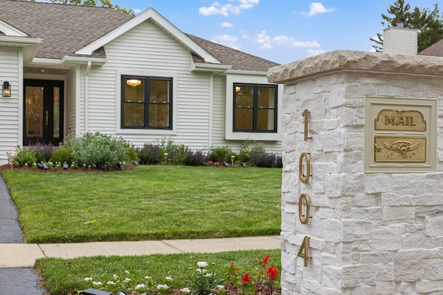 1004 Golden Ave, Woodstock, IL 60098 - exterior space with stone siding, a chimney, roof with shingles, and a front yard