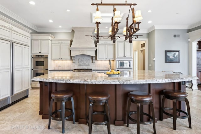 kitchen featuring visible vents, backsplash, light stone counters, custom range hood, and appliances with stainless steel finishes