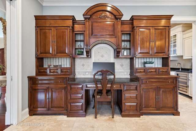 office space with built in desk, wine cooler, a sink, crown molding, and baseboards