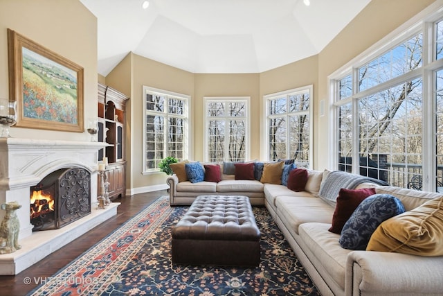 living room with a high ceiling, baseboards, a fireplace, built in shelves, and dark wood-style flooring