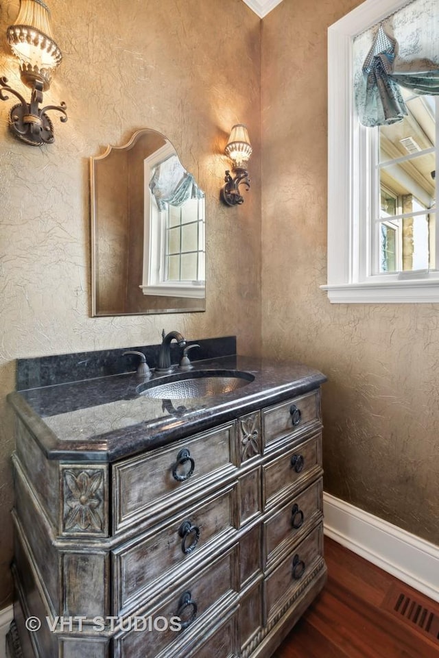 bathroom featuring baseboards, wood finished floors, visible vents, and a wealth of natural light