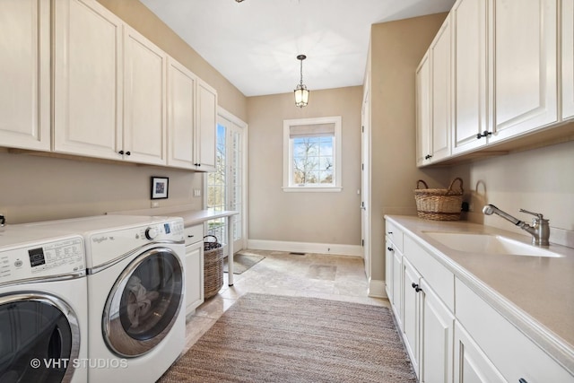 laundry area with light tile patterned floors, washing machine and dryer, a sink, baseboards, and cabinet space