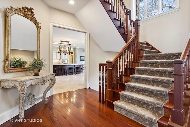 staircase featuring recessed lighting, hardwood / wood-style floors, and a notable chandelier