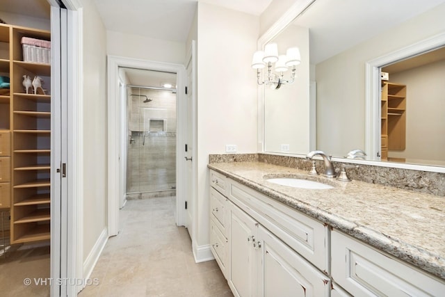 bathroom featuring tile patterned floors, vanity, a walk in closet, tiled shower, and a notable chandelier