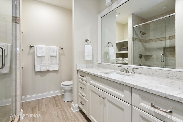 full bathroom featuring a shower stall, wood finished floors, toilet, vanity, and baseboards
