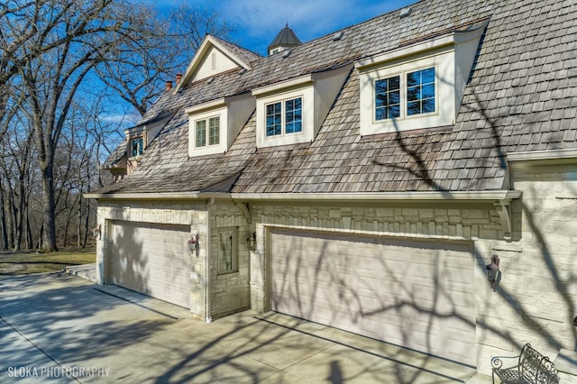 view of side of property with a garage, a chimney, and concrete driveway