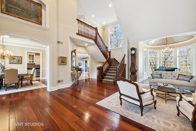 living room featuring hardwood / wood-style floors, visible vents, a towering ceiling, and a notable chandelier
