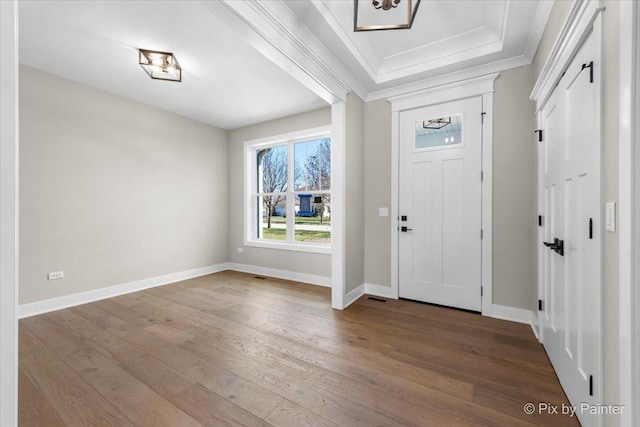 entryway featuring baseboards, ornamental molding, wood finished floors, and visible vents