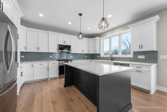 kitchen with stainless steel appliances, light wood-style floors, a kitchen island, decorative backsplash, and white cabinetry