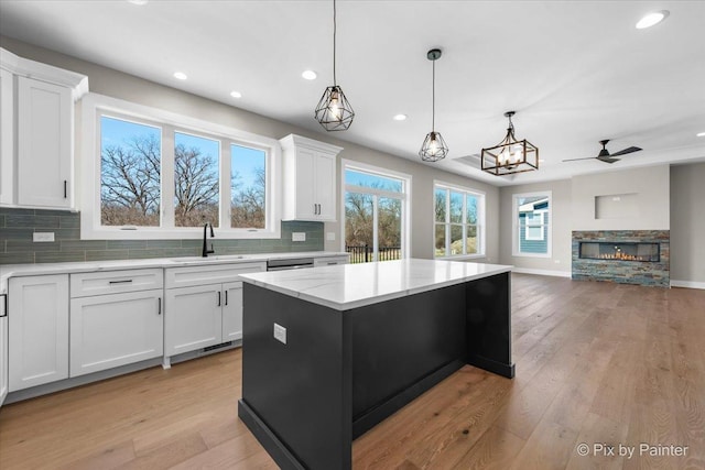 kitchen with a sink, tasteful backsplash, open floor plan, recessed lighting, and white cabinetry