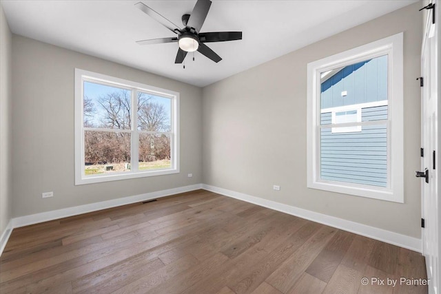 unfurnished room with visible vents, baseboards, wood finished floors, and ceiling fan