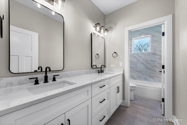 bathroom featuring toilet, a sink, double vanity, and bathing tub / shower combination