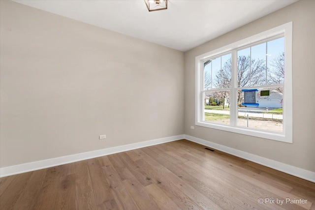 spare room featuring visible vents, wood finished floors, and baseboards