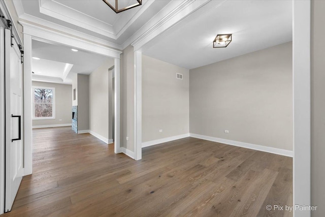 interior space with crown molding, baseboards, wood finished floors, and a barn door