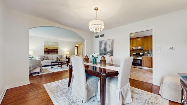 7350 N Karlov Ave, Lincolnwood, IL 60712 - dining space with arched walkways, wood finished floors, and a chandelier