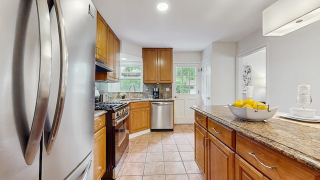 7350 N Karlov Ave, Lincolnwood, IL 60712 - kitchen with stainless steel appliances, under cabinet range hood, tasteful backsplash, brown cabinets, and light tile patterned floors