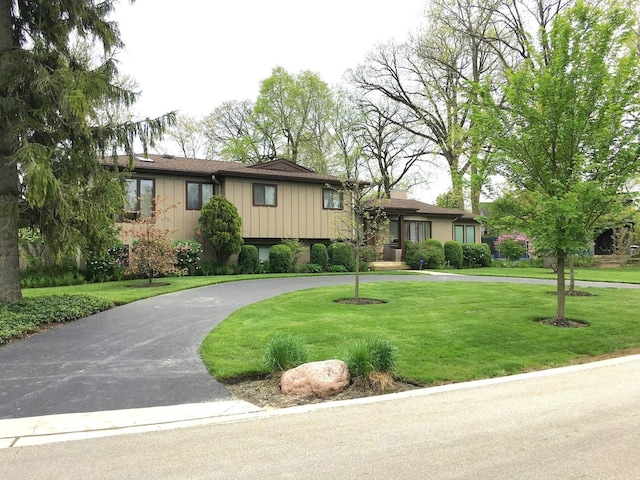 tri-level home with curved driveway and a front lawn