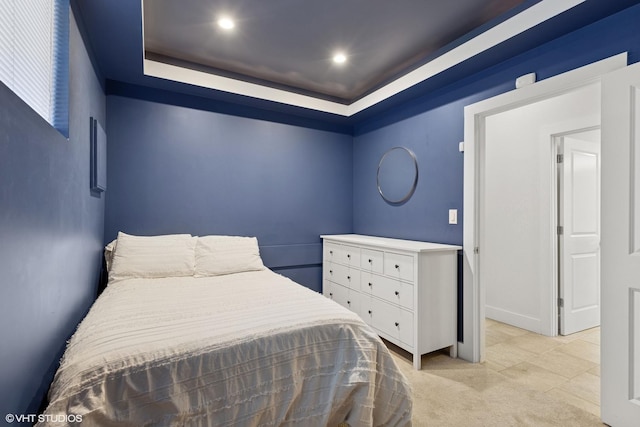 bedroom featuring recessed lighting, a tray ceiling, and light carpet