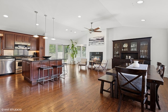 interior space featuring dark wood-style flooring, high vaulted ceiling, a glass covered fireplace, a ceiling fan, and recessed lighting