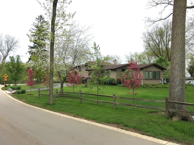 view of front facade featuring fence, a chimney, and a front lawn