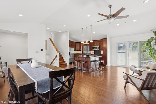 dining room featuring a ceiling fan, vaulted ceiling, stairs, dark wood-style floors, and recessed lighting