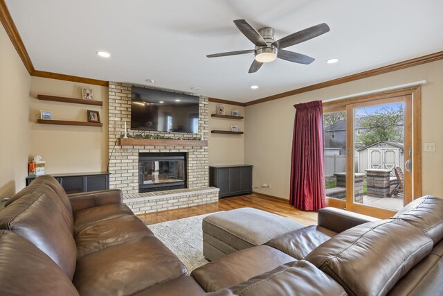 living room with ornamental molding, ceiling fan, and a brick fireplace