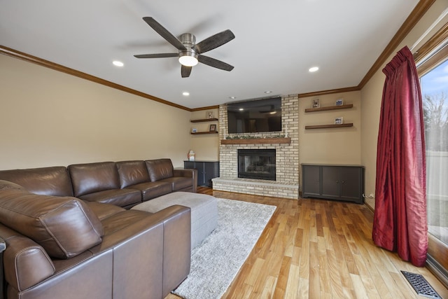 living room with wood finished floors, visible vents, ceiling fan, and ornamental molding