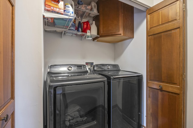 clothes washing area featuring cabinet space and separate washer and dryer