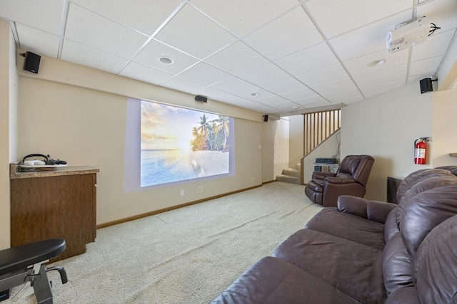 carpeted living room featuring baseboards, stairway, and a drop ceiling