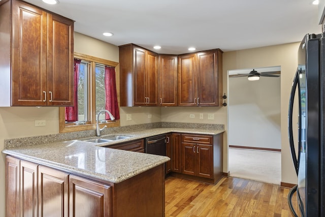 kitchen featuring recessed lighting, freestanding refrigerator, a sink, light wood-type flooring, and a peninsula