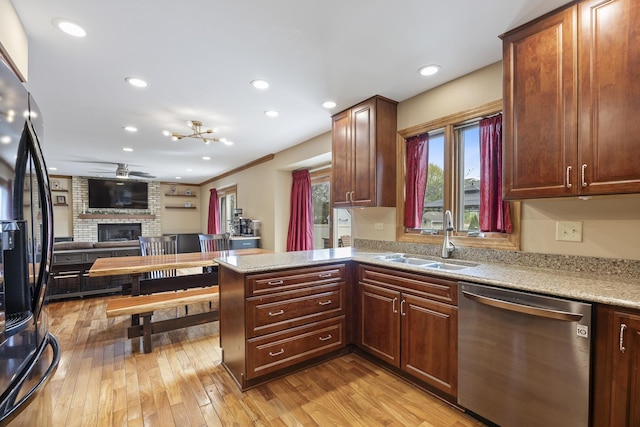 kitchen with stainless steel dishwasher, black fridge with ice dispenser, light wood-style floors, a fireplace, and a sink